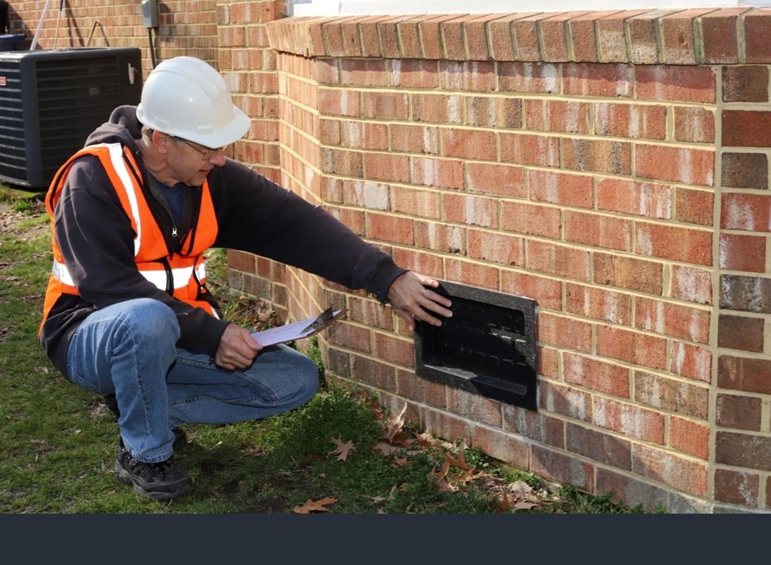 Inspector examining building's foundation vent.